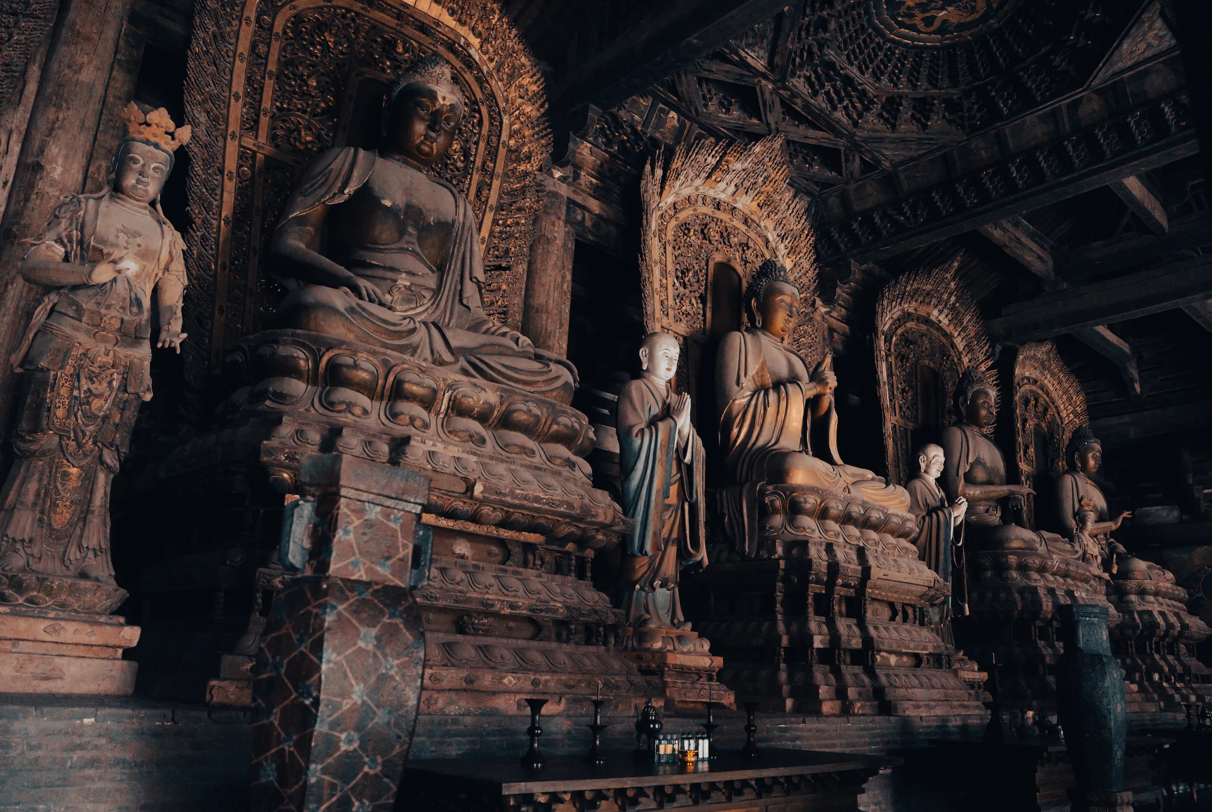 Painted clay figures gilded in a darkened temple hall in Datong