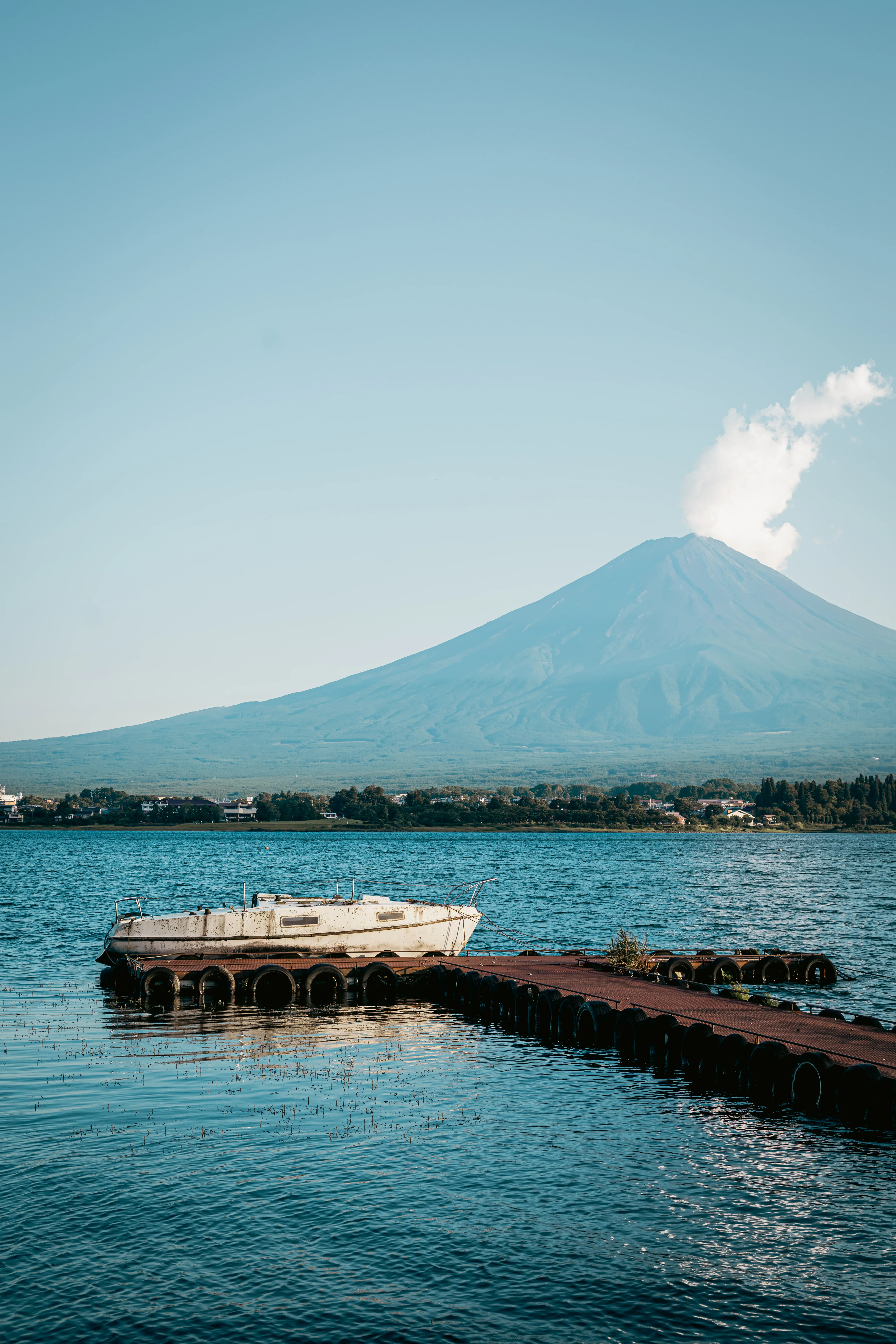 Mount Fuji beyond a wooden jetty and a white boat